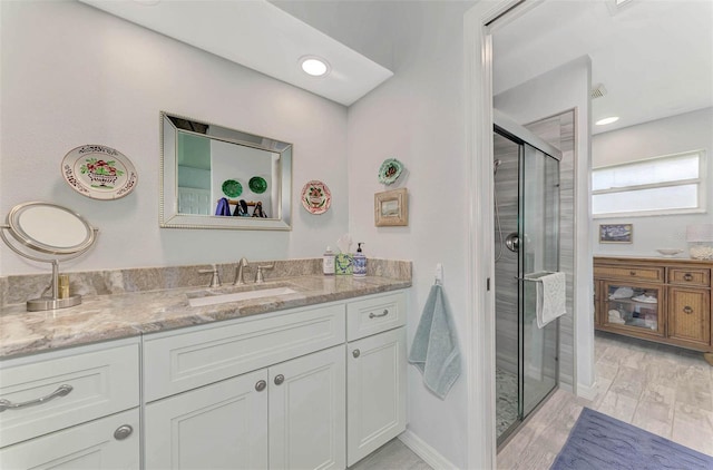 bathroom featuring wood-type flooring, an enclosed shower, and vanity