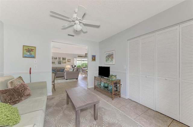 tiled living room with ceiling fan and a textured ceiling