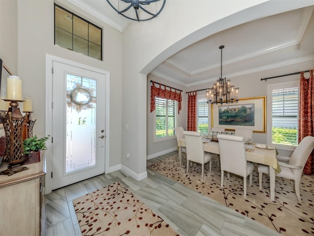 tiled foyer entrance featuring a wealth of natural light, a raised ceiling, an inviting chandelier, and crown molding