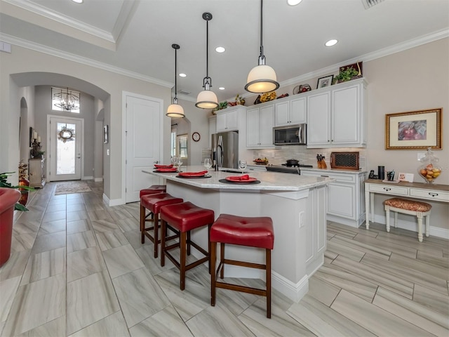 kitchen featuring light tile patterned floors, appliances with stainless steel finishes, white cabinets, and an island with sink