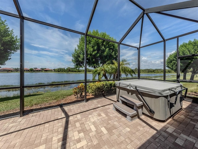 view of patio featuring a hot tub, a lanai, and a water view