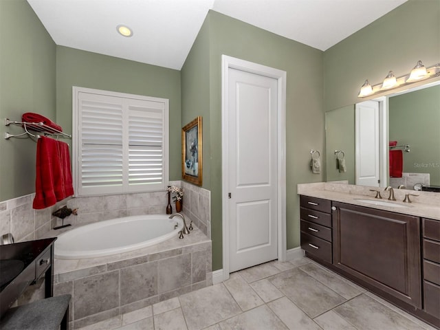 bathroom featuring tile patterned flooring, tiled tub, and vanity