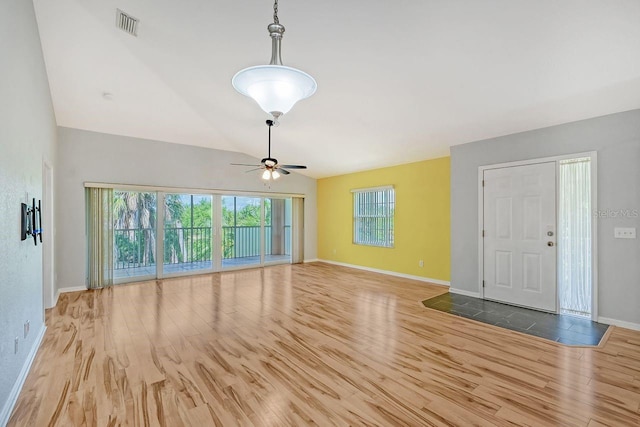 unfurnished living room featuring vaulted ceiling, hardwood / wood-style flooring, ceiling fan, and a wealth of natural light