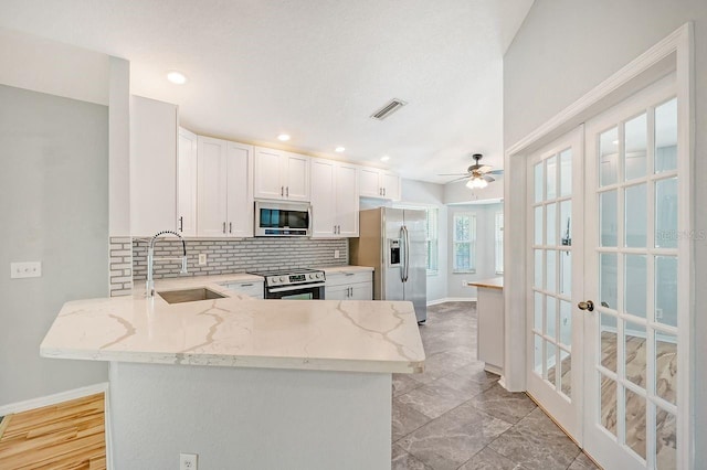 kitchen with white cabinets, appliances with stainless steel finishes, sink, kitchen peninsula, and ceiling fan