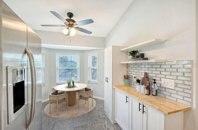 kitchen with butcher block countertops, stainless steel fridge with ice dispenser, white cabinetry, lofted ceiling, and ceiling fan