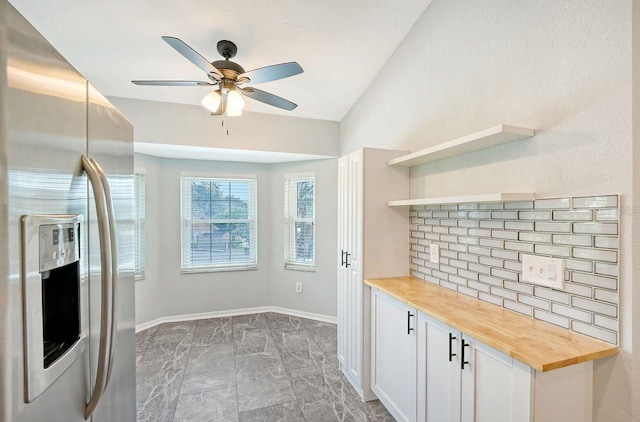 kitchen featuring wooden counters, ceiling fan, stainless steel fridge with ice dispenser, vaulted ceiling, and white cabinets