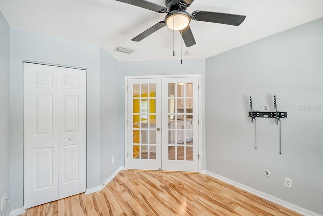 interior space with french doors, light hardwood / wood-style flooring, ceiling fan, and a closet