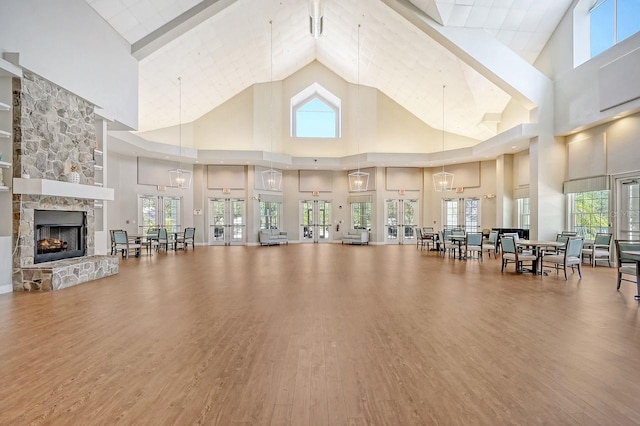 exercise room with high vaulted ceiling, hardwood / wood-style flooring, and a fireplace