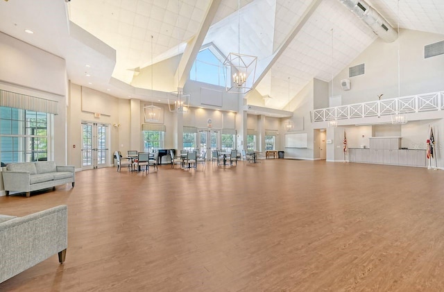 workout area featuring light hardwood / wood-style flooring, an inviting chandelier, and high vaulted ceiling