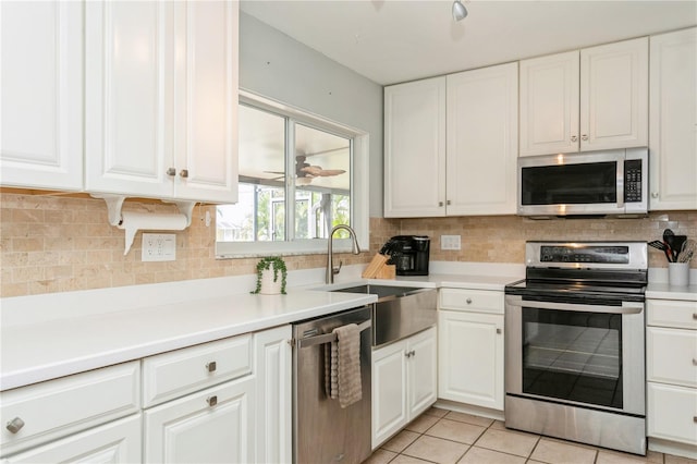 kitchen featuring sink, white cabinetry, backsplash, appliances with stainless steel finishes, and light tile patterned floors