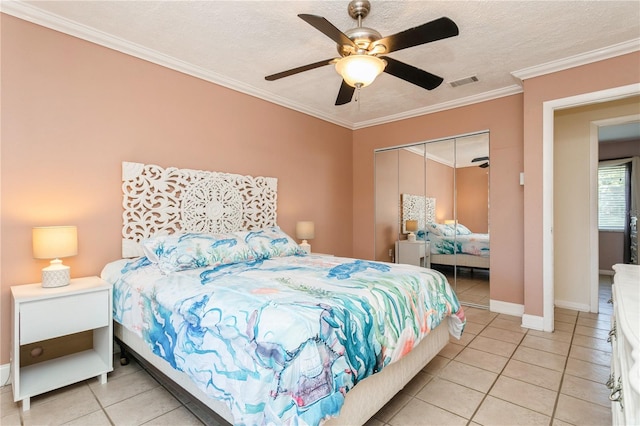 bedroom featuring ornamental molding, a closet, ceiling fan, and light tile patterned flooring