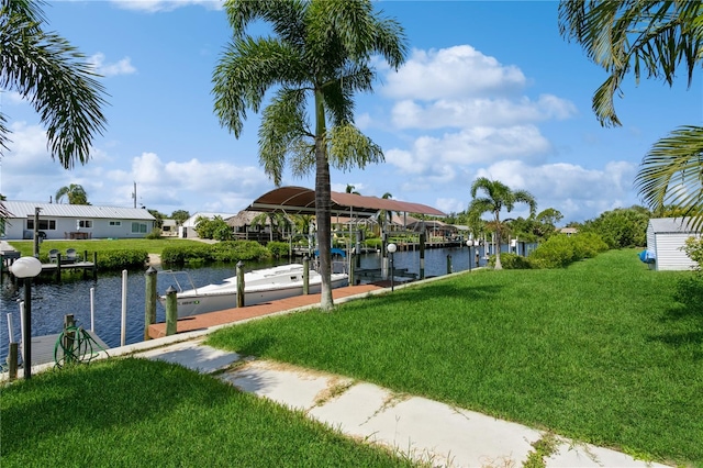 view of community with a boat dock, a lawn, and a water view