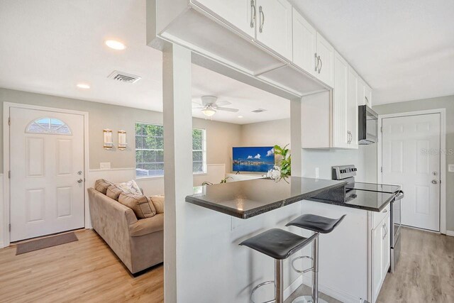 kitchen featuring white cabinetry, stainless steel appliances, kitchen peninsula, ceiling fan, and light hardwood / wood-style floors