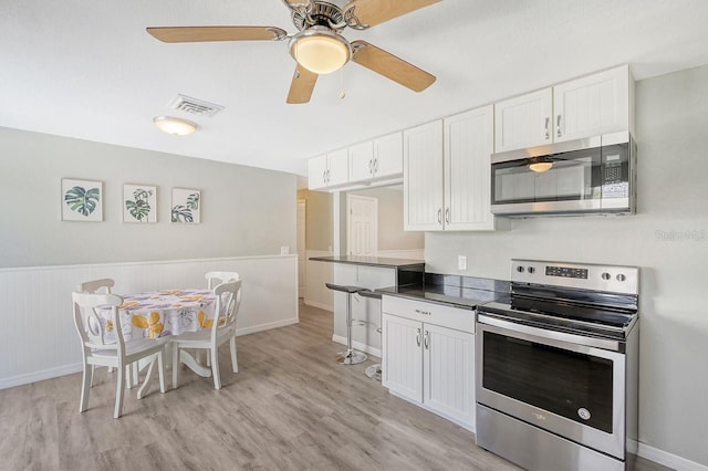 kitchen featuring white cabinets, ceiling fan, stainless steel appliances, and light hardwood / wood-style floors