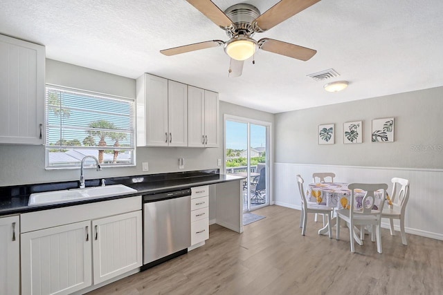 kitchen with light hardwood / wood-style floors, stainless steel dishwasher, sink, ceiling fan, and white cabinets