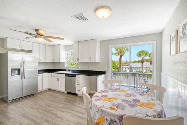 kitchen with light wood-type flooring, white cabinetry, sink, ceiling fan, and appliances with stainless steel finishes