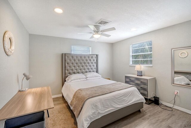 bedroom with light wood-type flooring, multiple windows, and ceiling fan