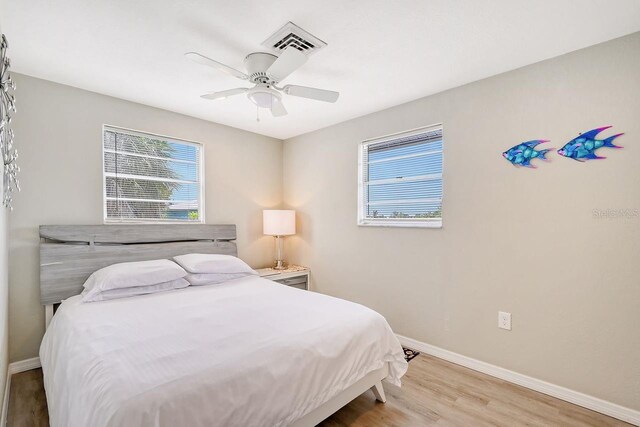 bedroom with multiple windows, hardwood / wood-style floors, and ceiling fan