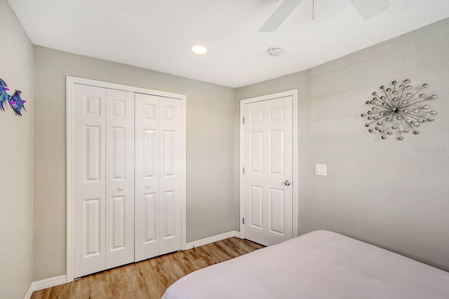 bedroom with light hardwood / wood-style flooring, ceiling fan, and a closet