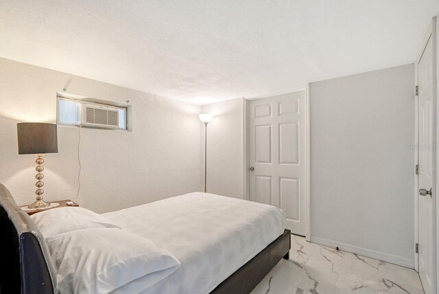 bedroom featuring a textured ceiling and an AC wall unit