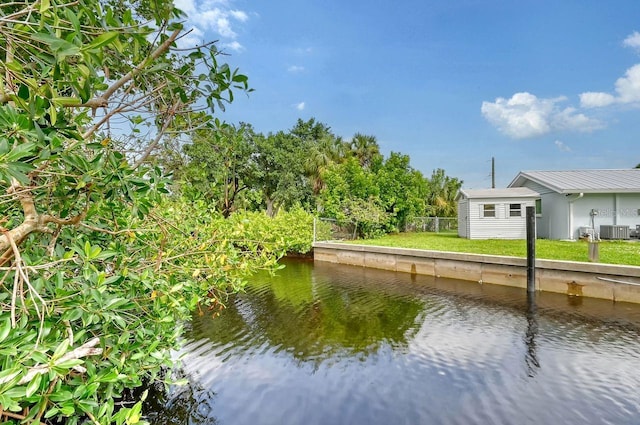 view of dock featuring central AC unit, a water view, and a yard