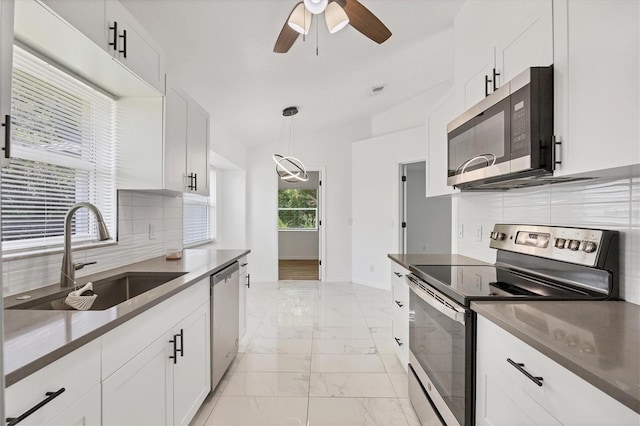 kitchen with white cabinetry, appliances with stainless steel finishes, light tile patterned floors, and backsplash