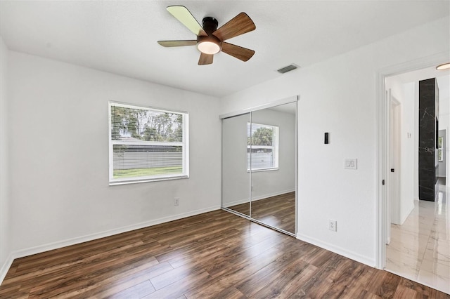 unfurnished bedroom featuring dark hardwood / wood-style flooring, a closet, and ceiling fan