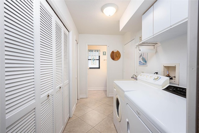 clothes washing area with cabinets, washer and clothes dryer, and light tile patterned flooring