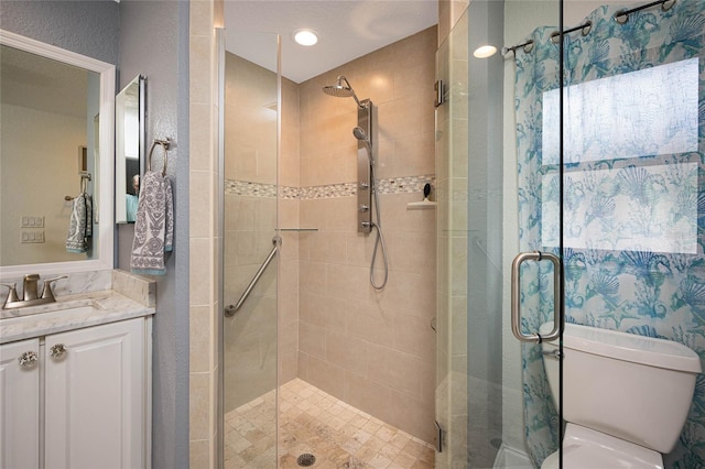 bathroom featuring a shower with door, vanity, and toilet