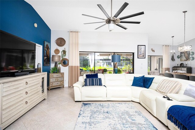 living area featuring light tile patterned floors, ceiling fan with notable chandelier, and lofted ceiling