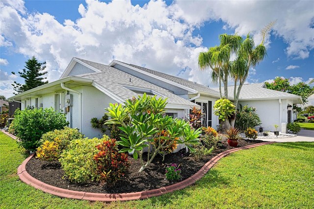 view of side of property with a garage, a yard, a shingled roof, and stucco siding