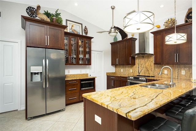 kitchen featuring appliances with stainless steel finishes, vaulted ceiling, a sink, a peninsula, and wall chimney exhaust hood