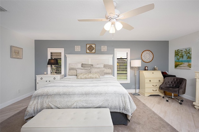 bedroom featuring ceiling fan, visible vents, baseboards, and wood finished floors