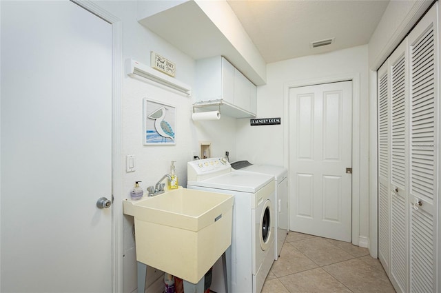 clothes washing area with light tile patterned floors, a sink, visible vents, cabinet space, and washing machine and clothes dryer