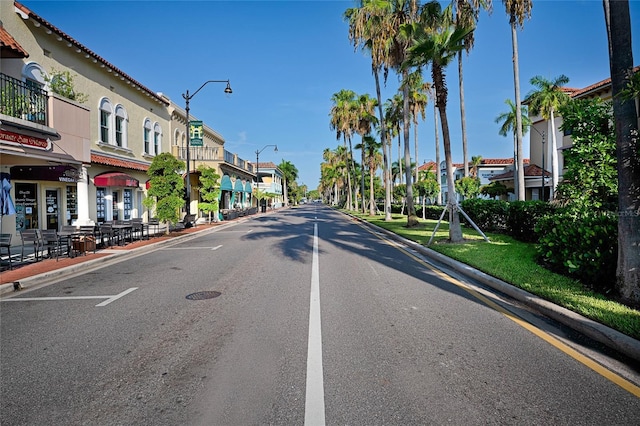 view of road featuring curbs, street lighting, sidewalks, and a residential view