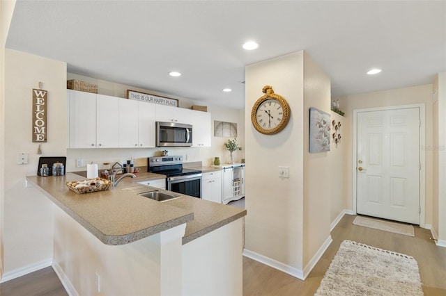 kitchen featuring light wood-type flooring, white cabinetry, appliances with stainless steel finishes, sink, and kitchen peninsula