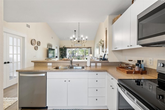 kitchen with stainless steel appliances, sink, lofted ceiling, white cabinets, and kitchen peninsula