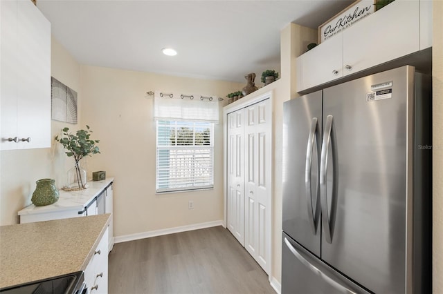 kitchen with white cabinetry, stainless steel fridge, and light hardwood / wood-style flooring