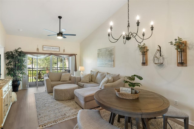 living room with hardwood / wood-style floors, ceiling fan with notable chandelier, and high vaulted ceiling