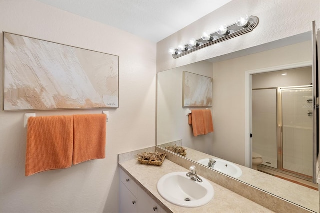 bathroom featuring toilet, a shower with door, and vanity