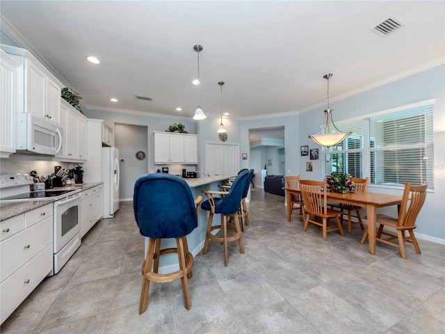 kitchen featuring pendant lighting, white cabinets, and white appliances