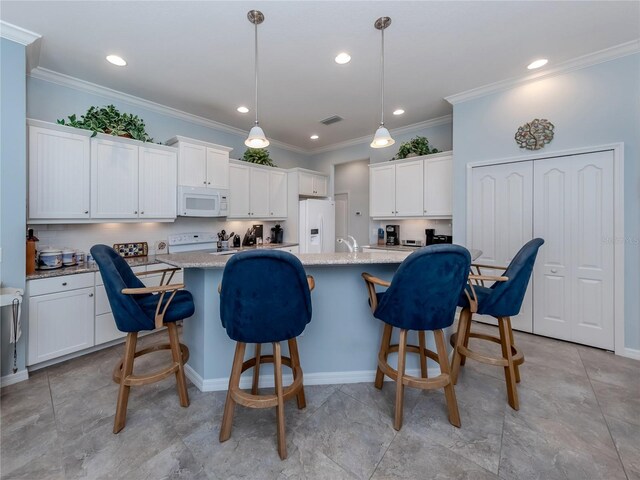 kitchen featuring decorative light fixtures, white appliances, a center island with sink, and white cabinetry