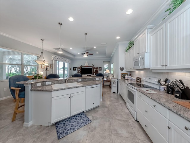 kitchen featuring white appliances, white cabinets, sink, ceiling fan, and a breakfast bar area