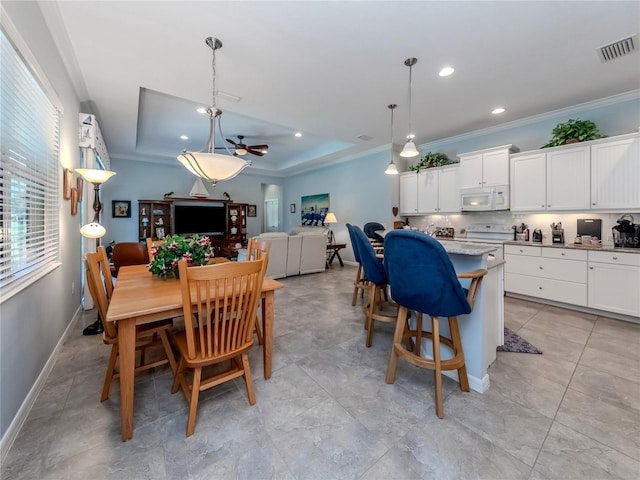 kitchen with white cabinetry, a raised ceiling, hanging light fixtures, and white appliances