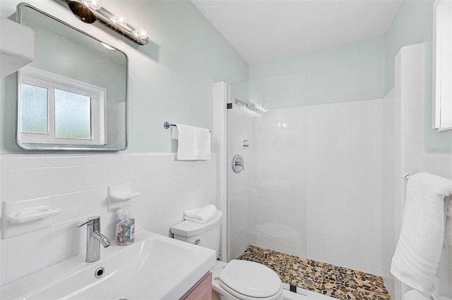 bathroom with backsplash, toilet, vanity, tile walls, and tiled shower