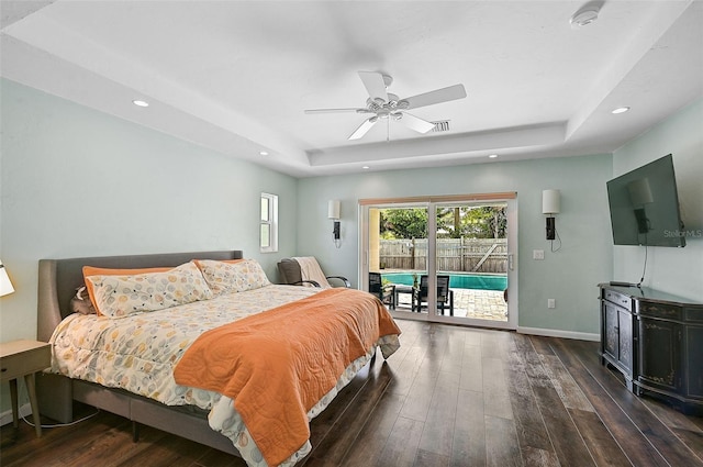 bedroom with ceiling fan, hardwood / wood-style floors, a raised ceiling, and access to exterior