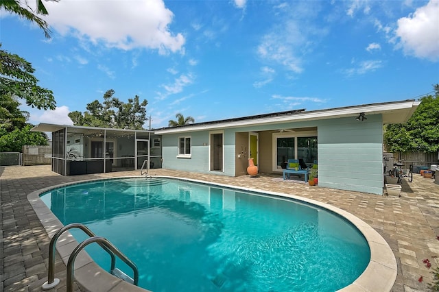 view of swimming pool featuring a sunroom, ceiling fan, and a patio