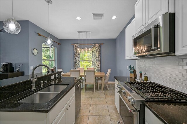 kitchen featuring sink, stainless steel appliances, light tile patterned flooring, and white cabinetry