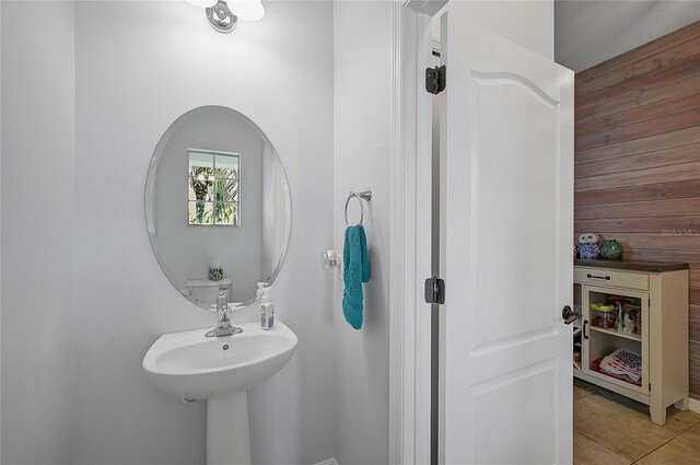 bathroom with tile patterned floors and wooden walls