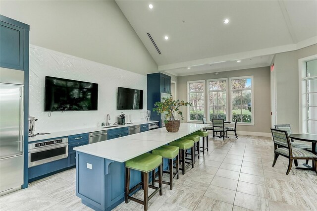 kitchen featuring appliances with stainless steel finishes, sink, a center island, light tile patterned flooring, and blue cabinets